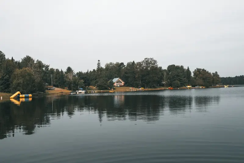 Cottage on a calm lakeshore with a boathouse