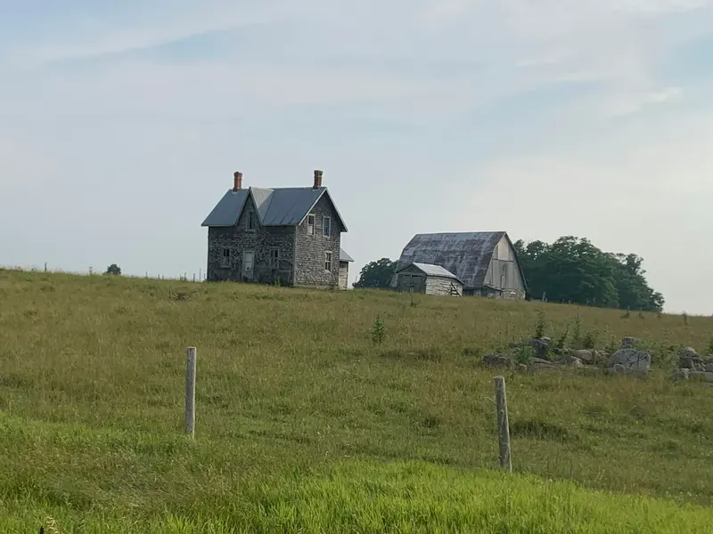 Stone farmhouse and barn in an open field