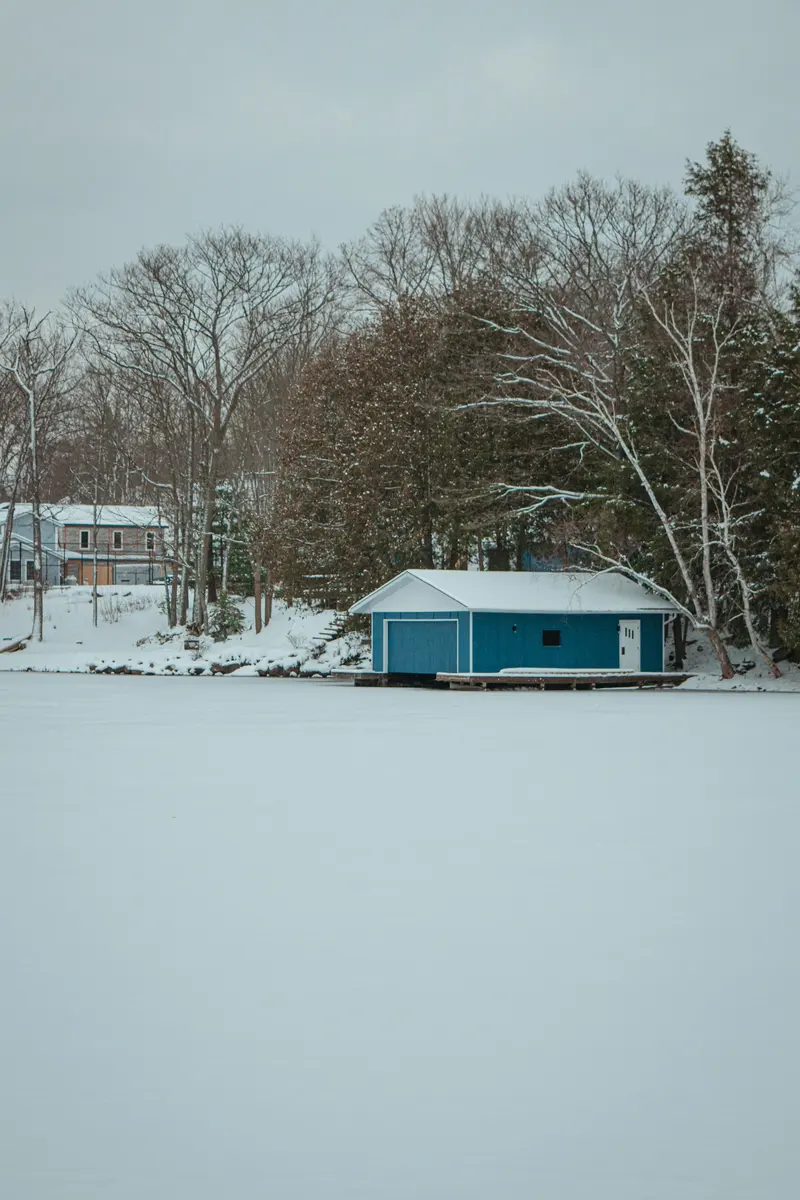 Small blue cabin on a frozen lake in snow