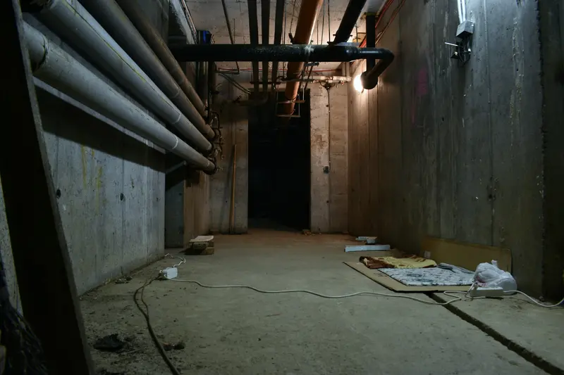 Unfinished basement with the drain and supply pipes exposed along the wall
