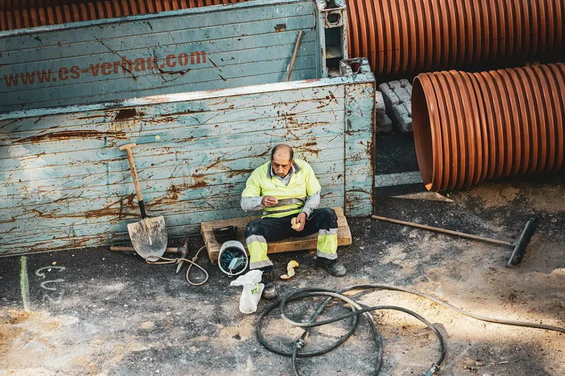 Worker beside a coil of orange corrugated drainage pipe