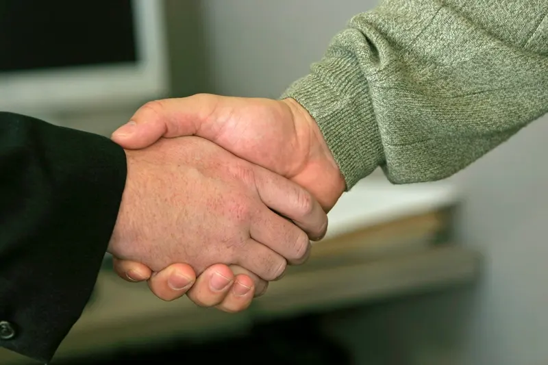 Two people shaking hands over a table