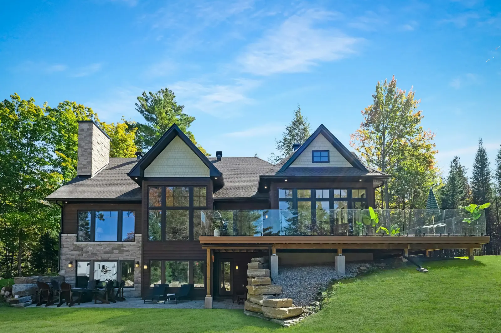 Large timber-and-stone house on a wooded lot with a lawn