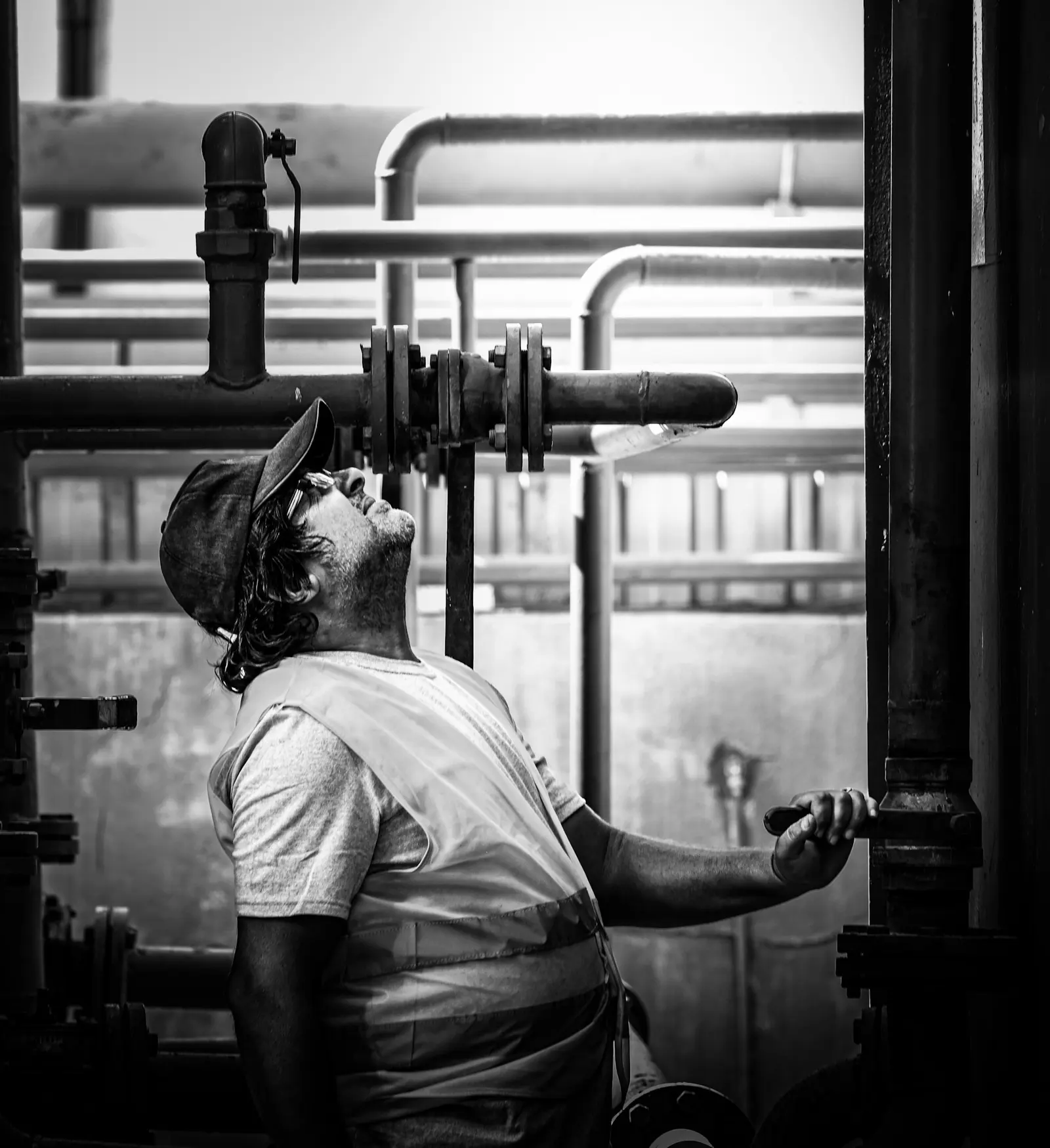 Worker checking pipes and valves in a mechanical room