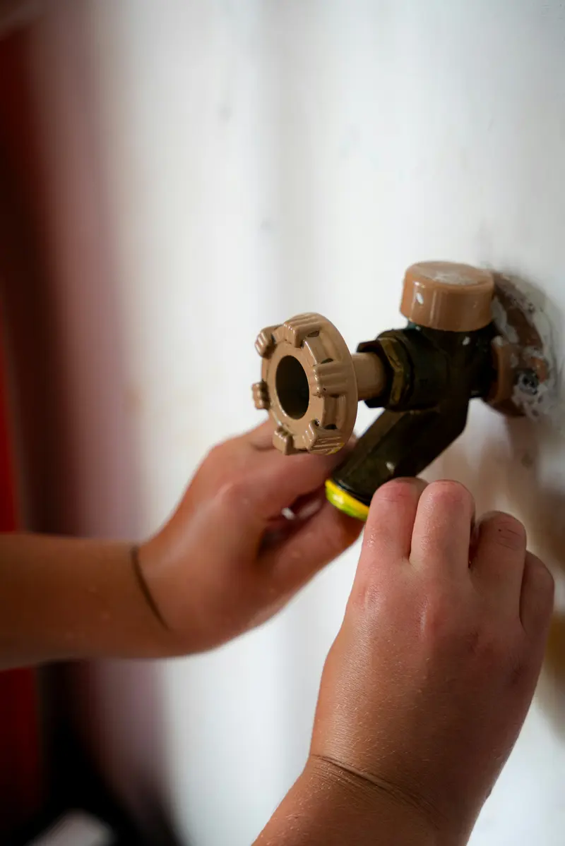 Hand turning a brass valve on a water pipe
